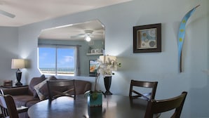 A dining area with a round table, chairs, a potted plant, and a ceiling fan. - Surf Beach 402 - Spectacular Sunsets - Beach Front (Treasure Island)