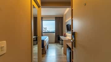 A hotel room with a bed, desk, and TV.