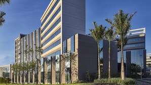 A modern building with a mix of glass and concrete facades, surrounded by landscaped areas with trees and shrubs. - Hotel Contemporâneo BY Royal Palm Hotels & Resorts (Campinas)
