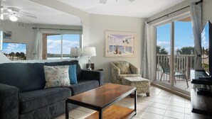 Un salon comprenant un canapé, un fauteuil et une table basse, une télévision, ainsi qu’un balcon avec vue.