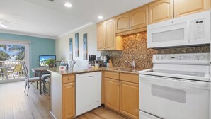 A modern kitchen with wooden cabinets, a granite countertop, a built-in microwave, and a dishwasher.