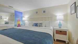 A hotel room with a bed, bedside tables, a nightstand, a mirror, and a wall with framed artwork.