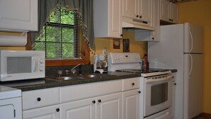 Una cocina con armarios blancos, un microondas, una estufa y un refrigerador.