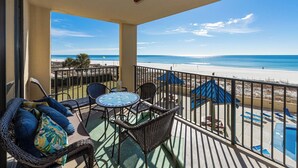 A balcony with wicker furniture, a small table, and a view of the beach and ocean. - Coastal 2BR Gulf Front Condo - Phoenix V 213 (Orange Beach)