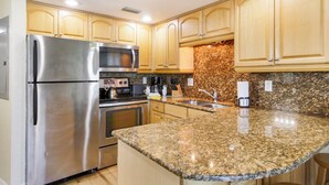Una cocina con electrodomésticos de acero inoxidable, encimeras de granito y armarios de madera.
