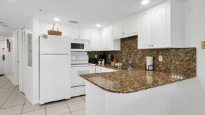 Eine moderne Küche mit weißen Schränken, einer Granit Arbeitsplatte und einem eingebauten Backofen.