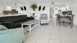 Ein modernes Wohnzimmer mit einem schwarzen Sofa, einem gestreiften Sessel, einem Couchtisch und einem Essbereich mit rundem Tisch und Stühlen.