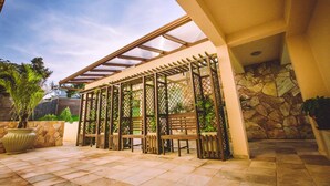 A covered outdoor seating area with wooden benches and a pergola structure. - Hotel Dom Otto (Vespasiano)