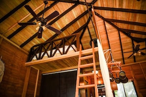 A wooden interior with a sloped ceiling, a ceiling fan, a ladder, and hanging pots. - Alicat Villas (Tulum)