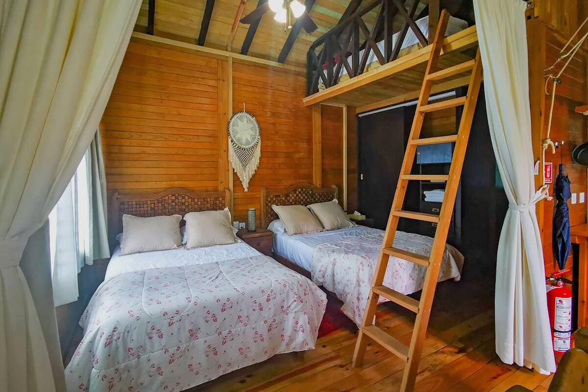 A cabin with two wooden bunk beds, a ceiling fan, and a wooden ladder.