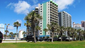 A multi-story hotel with balconies, surrounded by palm trees and parked vehicles. - Meridian Plaza by Palmetto Vacations (Myrtle Beach)
