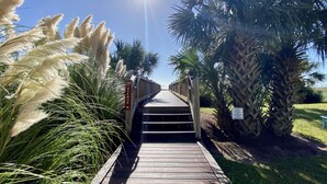A wooden boardwalk leading to a building with a sign reading "23rd Avenue." - Meridian Plaza by Palmetto Vacations (Myrtle Beach)