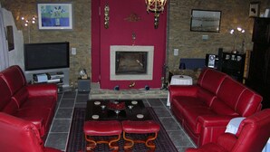Una sala de estar con sofás de cuero rojo, una mesa de centro y una chimenea.