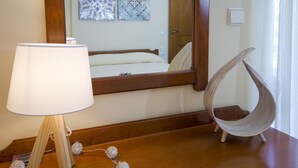 A room with a wooden bedside table, a hanging chair, a lamp, and two wall-mounted artworks. - Sea Daffodil Apartments (Kissamos)