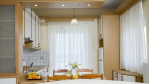 A bedroom with a bed, two pillows, a bedside table, a mirror, and a view of a kitchen and dining area. - Sea Daffodil Apartments (Kissamos)