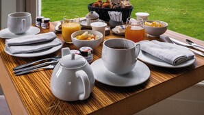 A breakfast table with a view of a golf course through a window.
