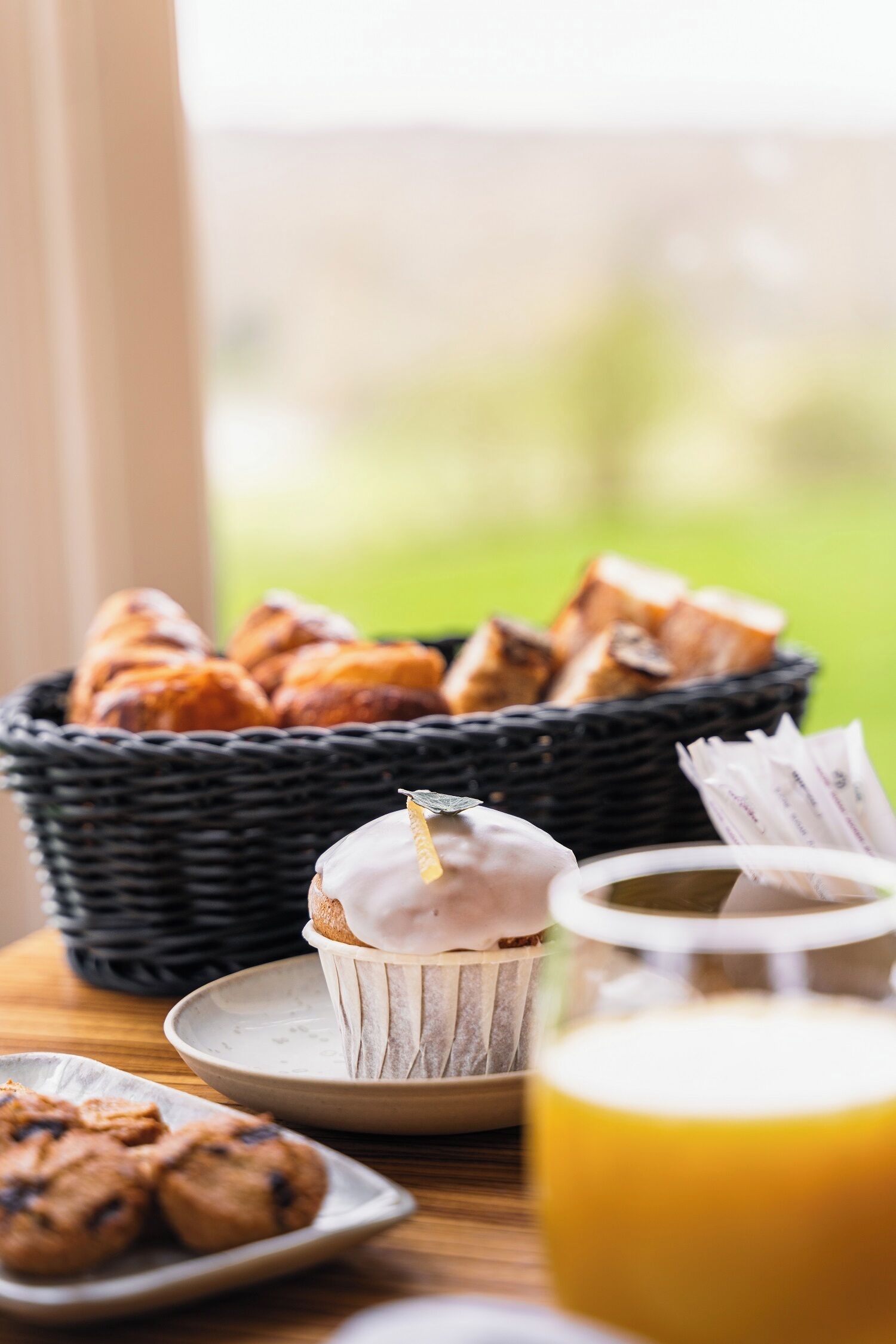 Ein Frühstückstisch mit Gebäck, einem Muffin und einem Glas Orangensaft.