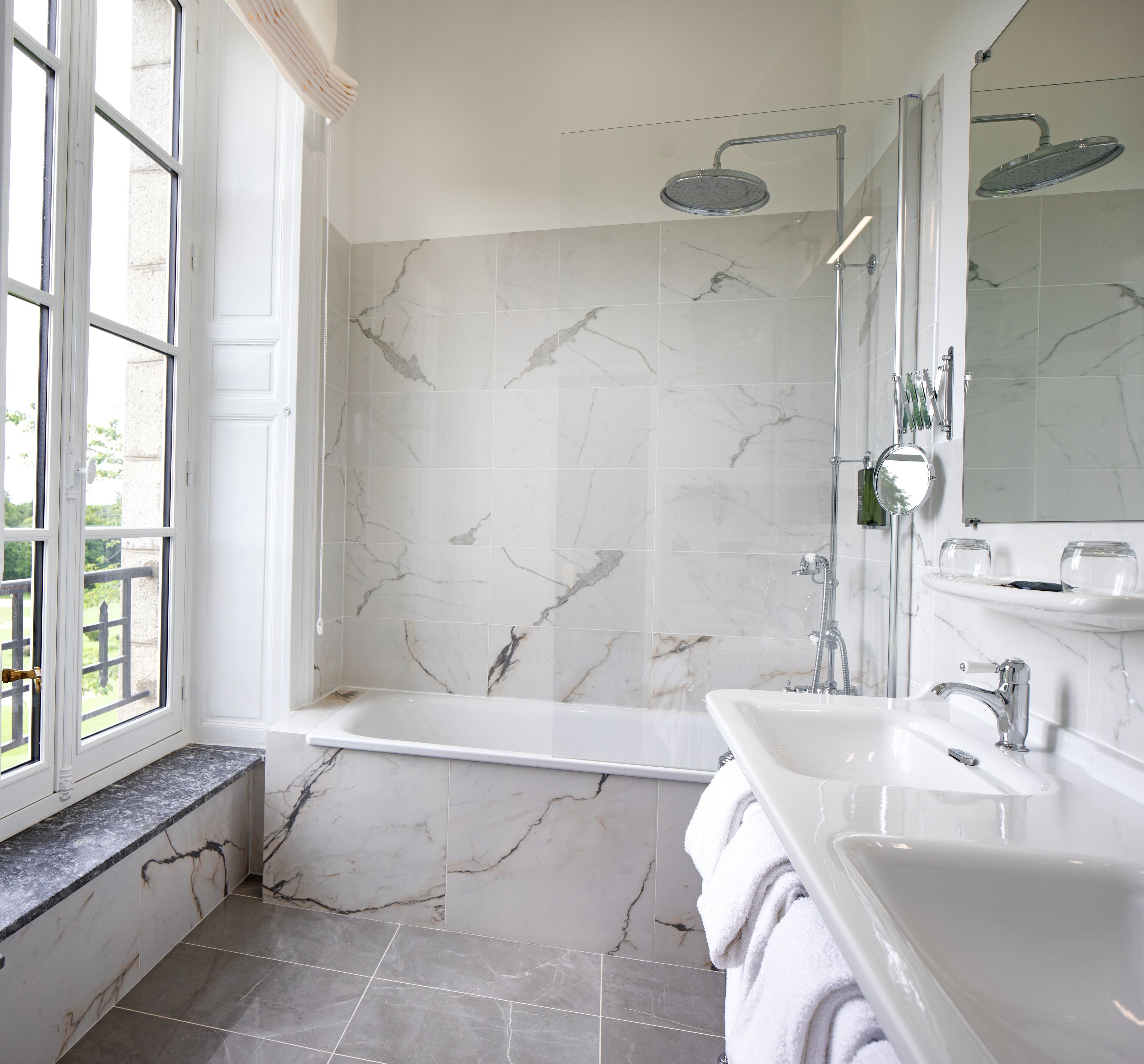 A bathroom with a bathtub, a shower, a sink, and a large mirror.