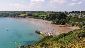 A coastal town with a sandy beach, boats, and lush greenery.