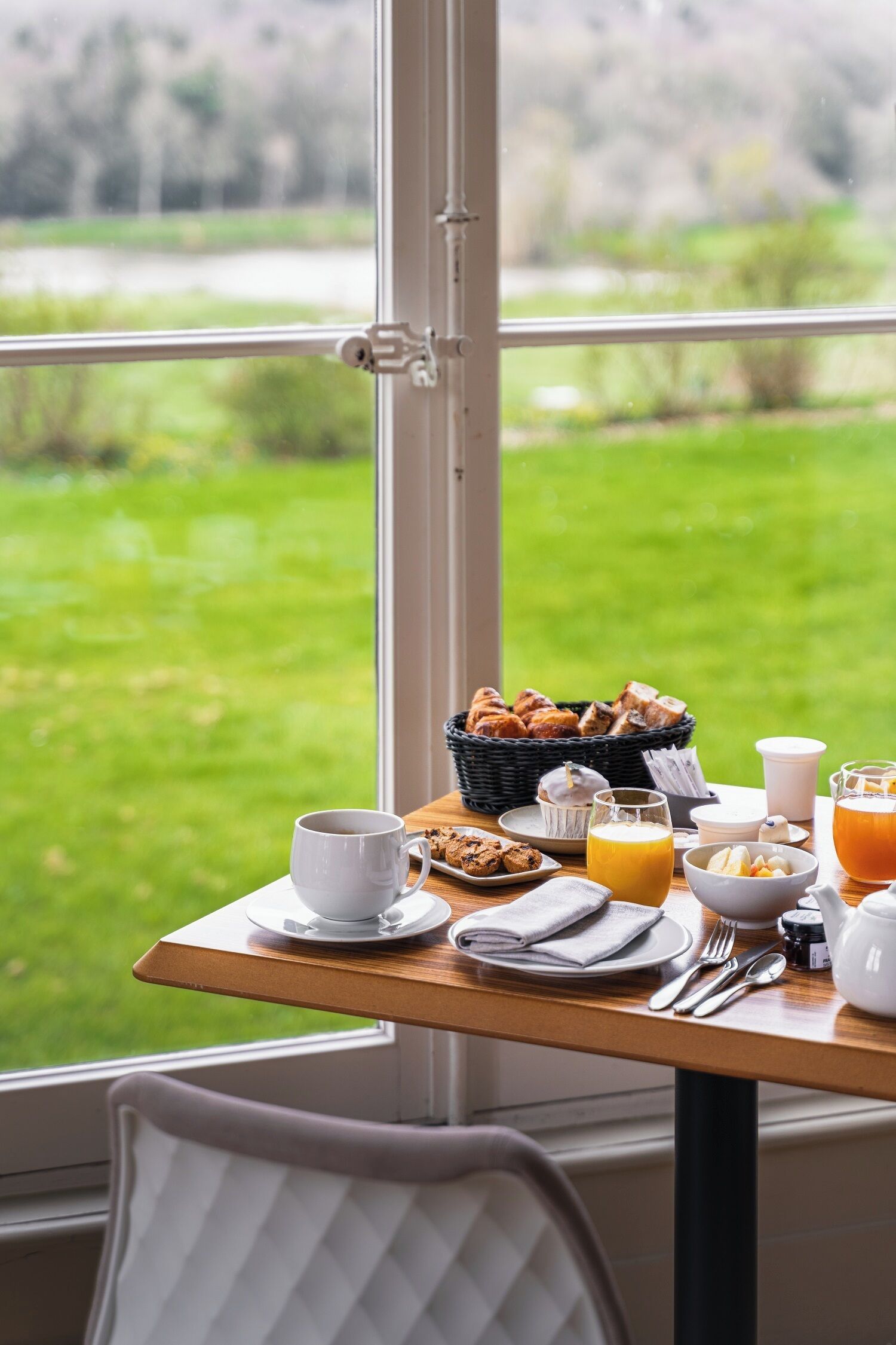 Een ontbijttafel met uitzicht op een groen landschap door een raam.