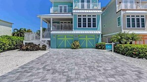 A beachfront property with a two-story building, a covered porch, and a driveway leading to a garage.