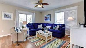 Un salon avec un canapé bleu, une table basse blanche et un tapis à rayures.