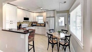 Une cuisine moderne avec des meubles blancs, un îlot central et un coin repas avec des chaises.