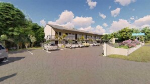 A building with a parking lot and several cars. - Deluxe King Gulf View Rm 104 Apartment 1 (Holmes Beach)