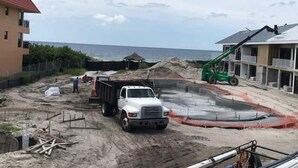 A construction site with a white truck, a green crane, and a building under construction near the beach. - Deluxe King Gulf View Rm 214 Apartment 1 (Holmes Beach)