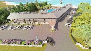 An aerial view of a hotel with a parking lot, a swimming pool, and a beach view.