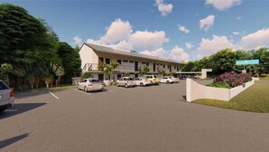 Un hotel con aparcamiento, varios coches y un edificio de techo plano con numerosas ventanas.