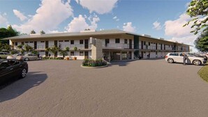 Un hotel moderno con un patio central, varios pisos y un estacionamiento con varios coches.