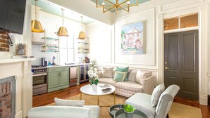 A spacious living room with a fireplace, a sofa set, a coffee table, and a kitchen area with modern appliances. - 154 ABC Spring Street - 7 BR / 5 BA Holiday home 7 (Charleston)