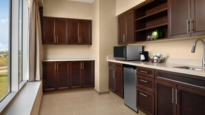 A modern kitchen with dark wood cabinets, a stainless steel refrigerator, and a built-in dishwasher. - Hyatt Place Calgary Airport (Calgary)