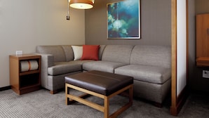 Una sala de estar moderna con un sofá modular, una mesa de centro de madera, una mesita auxiliar y una lámpara de pared.