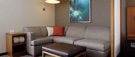 A modern living room with a sectional sofa, a wooden coffee table, a side table, and a wall-mounted lamp.