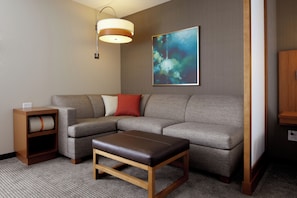 A modern living room with a sectional sofa, a wooden coffee table, a side table, and a wall-mounted lamp.