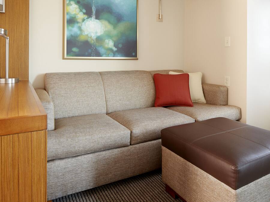 A modern living room with a sofa, ottoman, and a wooden side table.