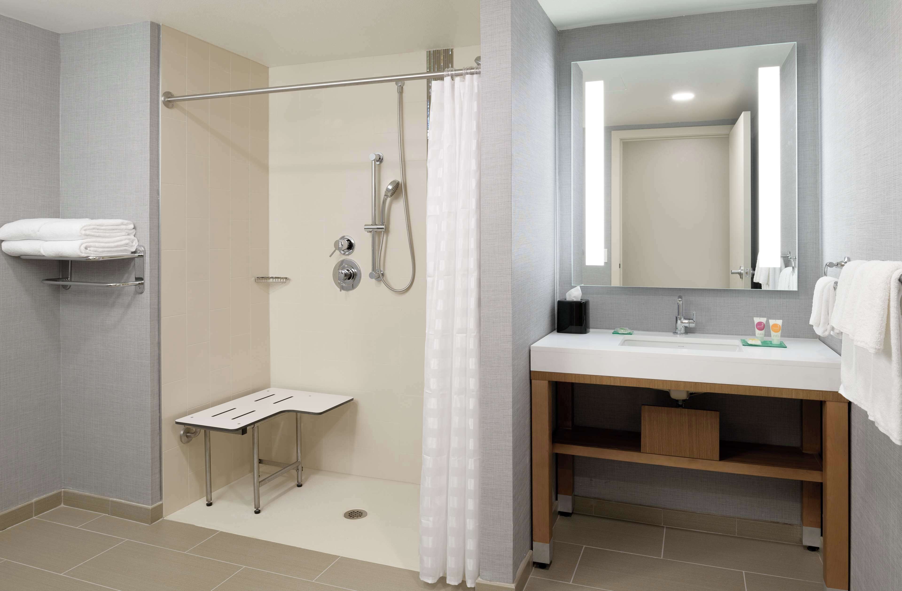 Un baño moderno con ducha, lavamanos, espejo y toallero.