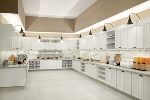 A modern kitchen with white cabinets, black pendant lights, and a tiled floor. - Hyatt Place Pasadena (Pasadena)