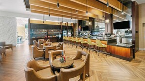 Un espace bar moderne avec un plafond en bois, des tabourets de bar et un comptoir doté d’un téléviseur à écran plat.