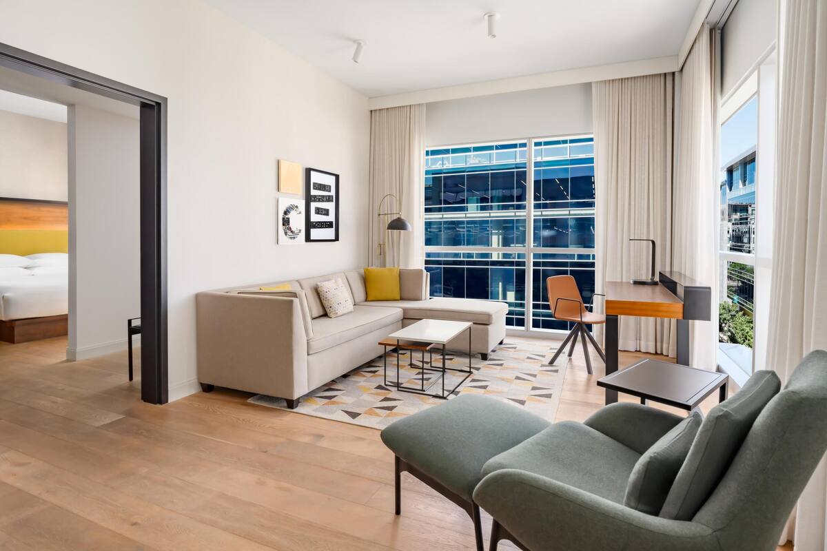 A modern living room with a sofa, armchairs, a coffee table, and a dining area.