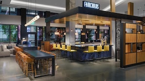 Un espace bar moderne avec un comptoir, des tabourets de bar jaunes et une enseigne portant l’inscription « FAIRCHILD’S ».