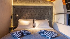 A bed with a tufted headboard, two white pillows, and striped pillows. - Anneta Studios (Igoumenitsa)