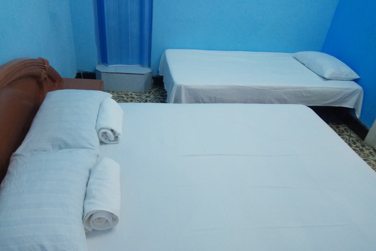 A hotel room with two beds, one with a brown headboard and the other with a white headboard.