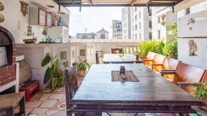 An outdoor patio with a long table and benches, surrounded by potted plants and decorative items. - Hostal Casa de Alexis y Mary (Havana)