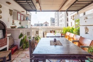 An outdoor patio with a long table and benches, surrounded by potted plants and decorative items. - Hostal Casa de Alexis y Mary (Havana)