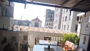 An outdoor patio with a wooden table and chairs, surrounded by potted plants and a tiled floor. - Hostal Casa de Alexis y Mary (Havana)