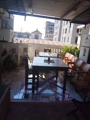 Enjoy al fresco dining in this charming outdoor space with a wooden table and chairs, surrounded by traditional buildings.
