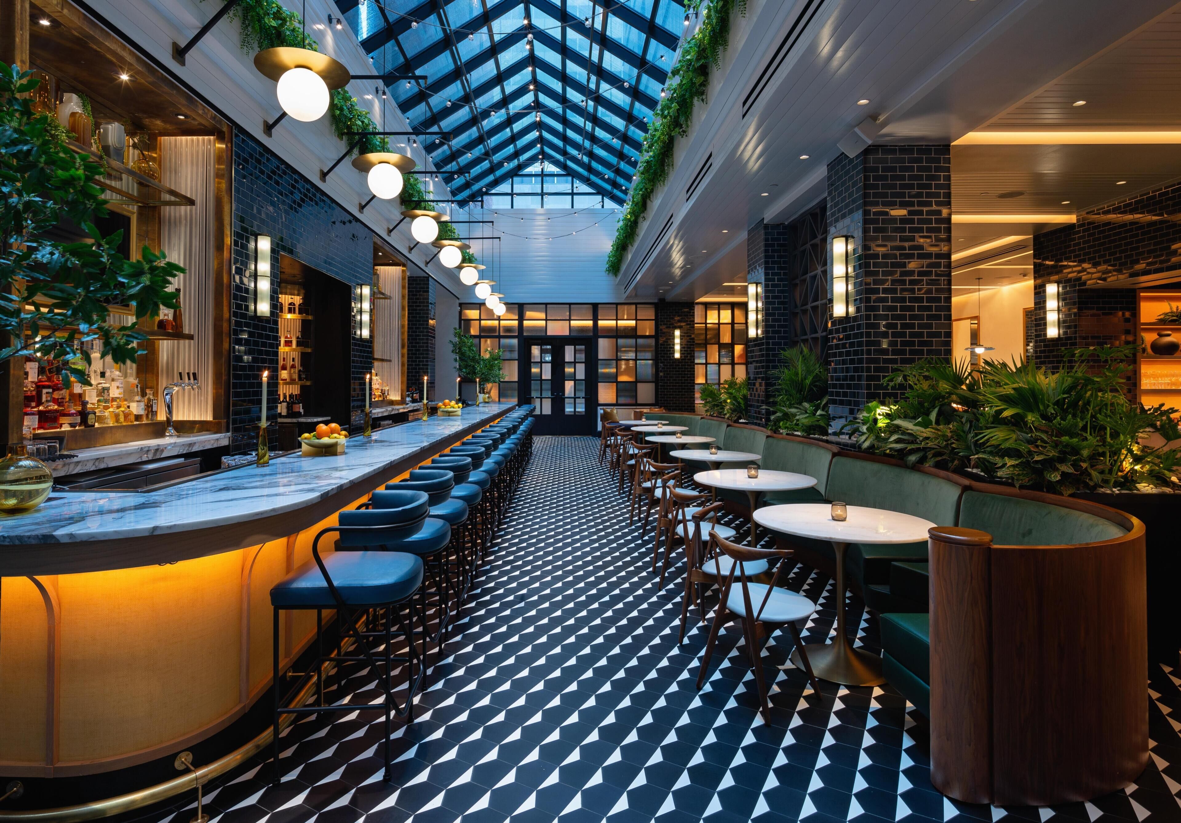 A modern bar area with a long counter, seating, and a patterned floor.